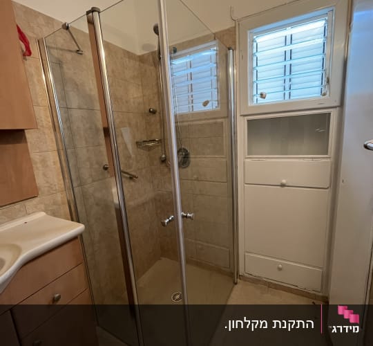 מקלחון זכוכית פינתי מותקן בחדר רחצה